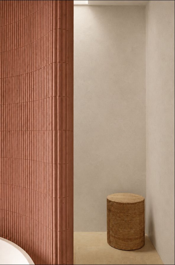 Fluted terracotta wall beside a travertine stool
