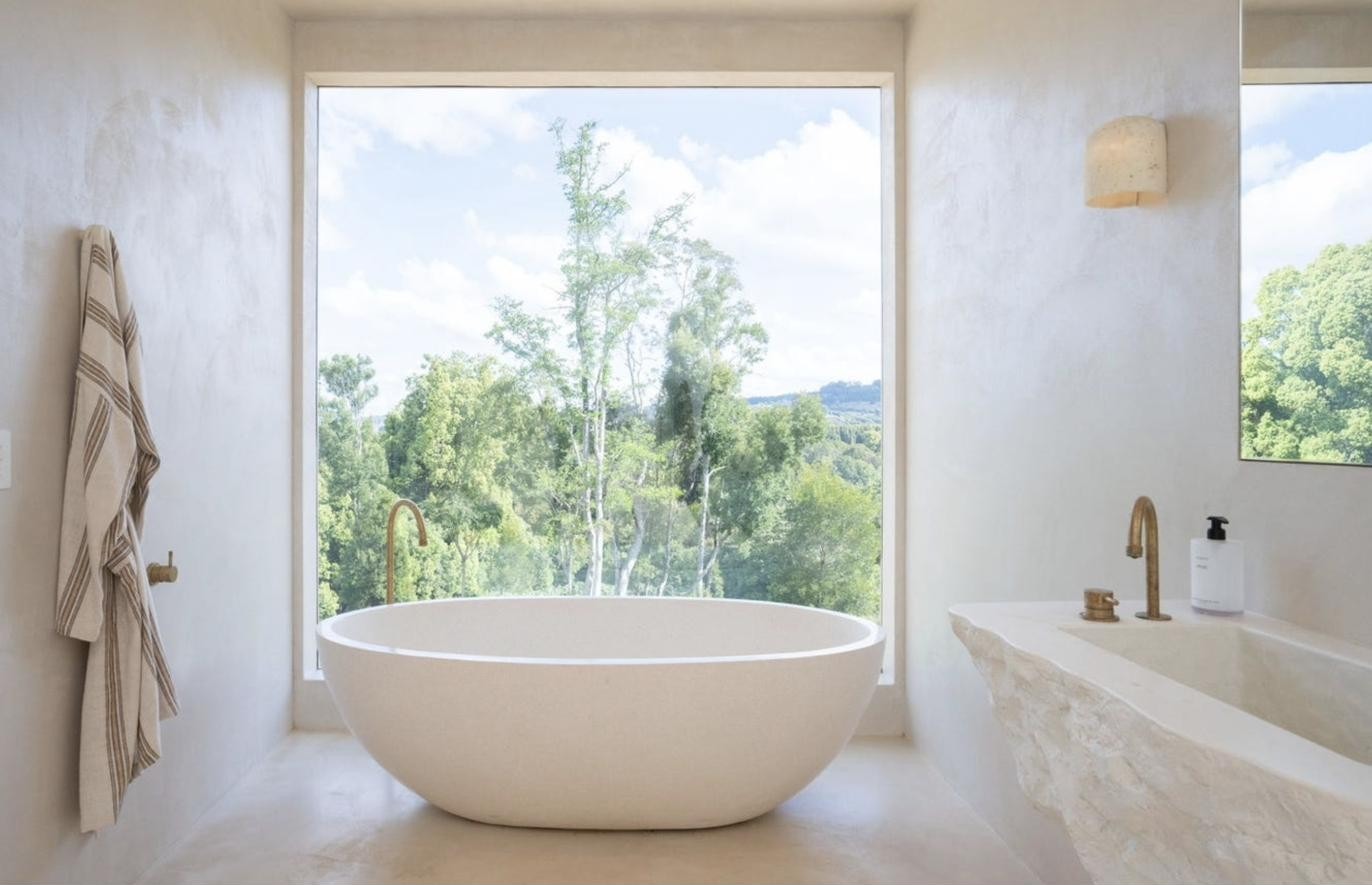 Freestanding bath facing a full-height window onto the rainforest, Komorebi Home