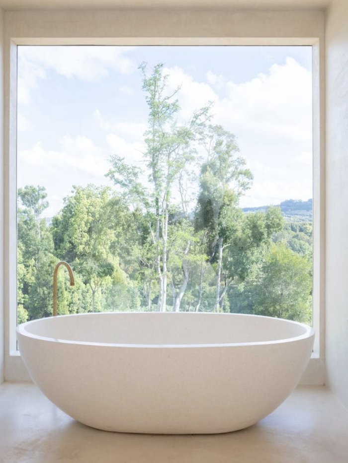 Freestanding bath facing a full-height window onto the rainforest, Komorebi Home