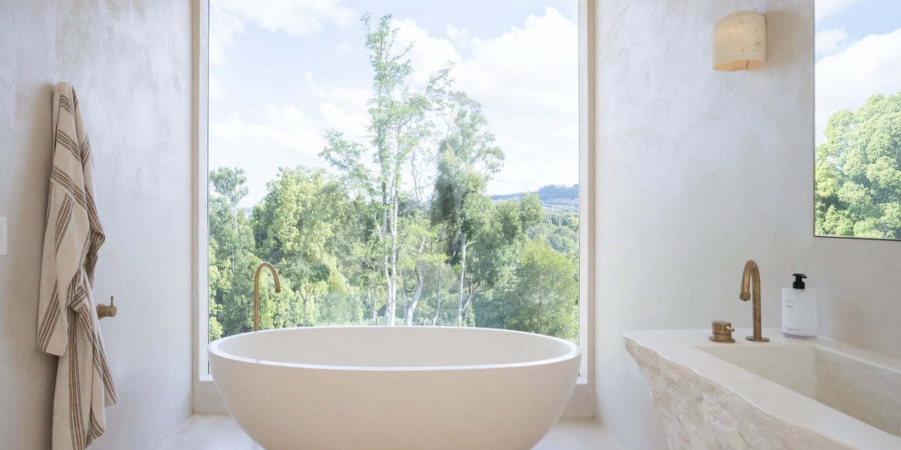 Freestanding bath facing a full-height window onto the rainforest canopy, Komorebi Home
