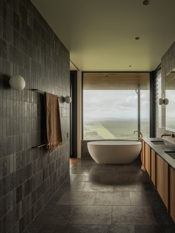 Ensuite bathroom with stone tiling and a freestanding bath overlooking the landscape, Newrybar Residence